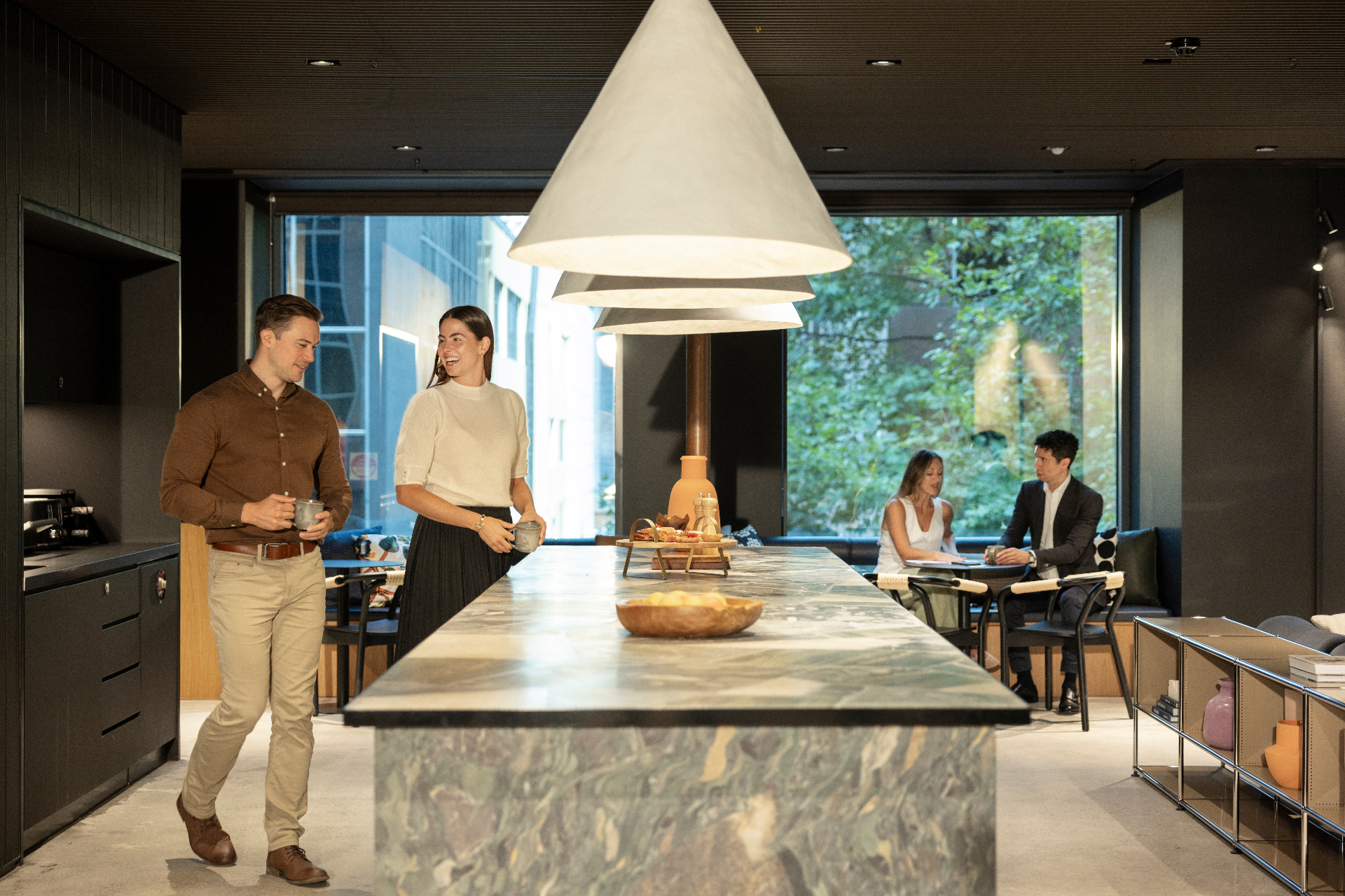 Members chatting over coffee at a marble kitchen island at Space&Co 530 Collins